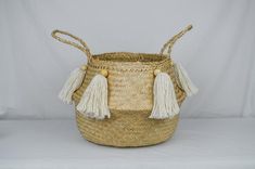 a woven basket with tassels on the handles and sides is shown in front of a white background