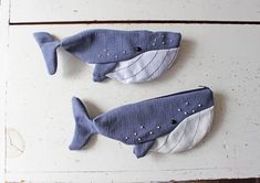 two blue and white stuffed whales sitting on top of a table