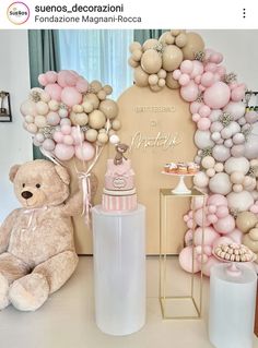 a teddy bear sitting in front of a balloon arch with balloons on it and a baby bottle next to it