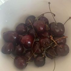 a white bowl filled with cherries on top of a table