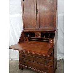 an old wooden desk with two drawers and a cupboard on the top, in front of a white backdrop