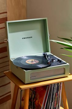 an old record player sitting on top of a table next to a potted plant