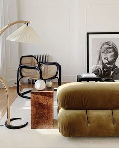 a living room filled with furniture next to a lamp and pictures on the wall behind it