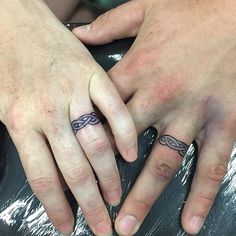 two people holding hands with tattoos on their fingers and the other hand has a ring