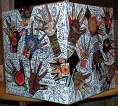 a large white box with lots of hand prints on the front and sides, sitting on top of a wooden table