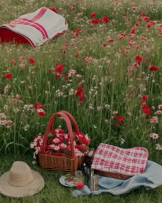 a picnic in the middle of a field full of red flowers and straw hats on top of it