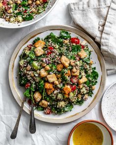 two plates filled with salad next to bowls of dressing