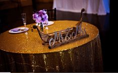 a table topped with a wooden sleigh filled with purple flowers and wine glasses