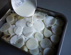 a pan filled with potatoes and milk being poured into it