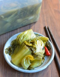 a white bowl filled with green vegetables next to chopsticks