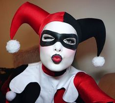 a woman with black and white makeup wearing a red and white clown mask on her face