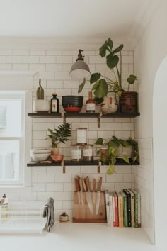 shelves with plants and books on them in a white tiled kitchen, next to a window