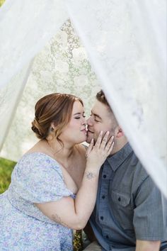 a man and woman are sitting under a white tent with their faces close to each other