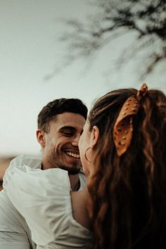 a man and woman standing next to each other with their arms around each other smiling