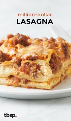 a white plate topped with lasagna covered in cheese and meats next to a fork