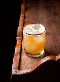 a glass filled with ice sitting on top of a wooden table