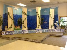 an empty room with blue and white curtains on the wall, decorated in greek style