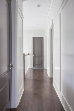 an empty hallway with white walls and wood floors is seen in this image from the front door