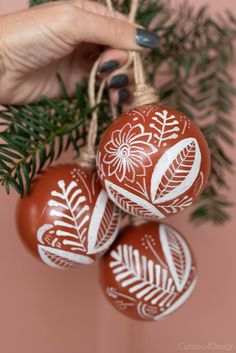 three faux burnished Mexican ornaments in a hand Terra Cotta Ornaments Diy Christmas, Barro Christmas Ornaments, Mexican Ornaments Diy, Terra Cotta Ornaments, Diy Mexican Decor, Terra Cotta Christmas, Christmas Decorating Themes, Burnished Pottery