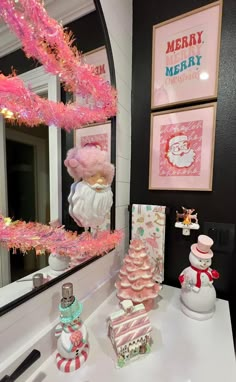 there is a pink christmas tree and other decorations on the counter in front of a mirror