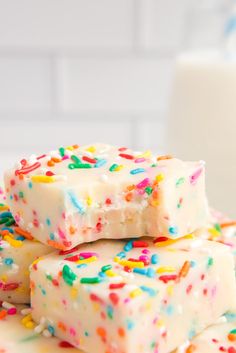 three pieces of cake with sprinkles stacked on top of each other next to a glass of milk