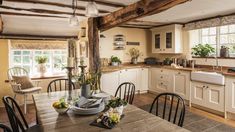 a kitchen filled with lots of wooden furniture and white cabinets next to a dining room table