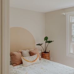 there is a bed with pillows and a plant in the corner on top of it