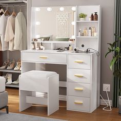 a white dressing table with mirror and stool in front of it, next to a gray chair