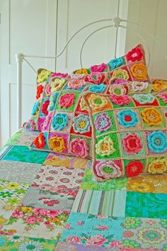 a bed topped with lots of colorful crocheted pillows