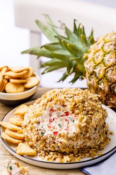 a pineapple sitting on top of a plate next to crackers and a cheese ball