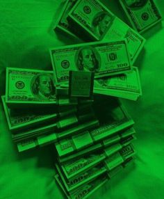 a pile of money sitting on top of a bed covered in green glower sheets