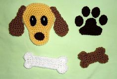 a crocheted dog's head, bone and paw prints on a green blanket