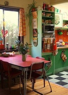 a kitchen with green walls and red table in the center, black and white checkered floor