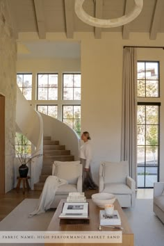 a living room with white furniture and a spiral stair case in the corner, as well as a woman walking up the stairs