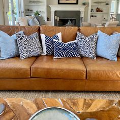 a living room filled with lots of brown couches covered in blue and white pillows