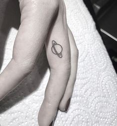 saturn tattoo on the left side of the arm and finger with an arrow in it