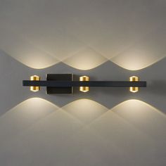 three lights that are on the side of a wall mounted light fixture in a room