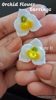 two crocheted flowers with yellow centers are being held by someone's hand