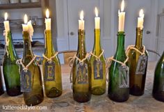 there are many wine bottles with candles in them