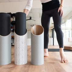 a woman standing next to three black and white vases on top of a wooden floor