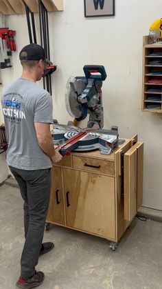 a man working on a piece of wood in a shop with tools and other items