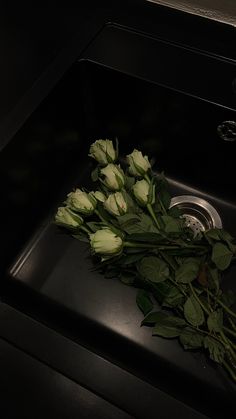 some white roses are laying on the black counter top in front of an oven and water faucet