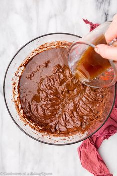 someone pouring chocolate into a glass bowl on top of a marble table with red napkins