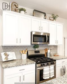 a kitchen with white cabinets and granite counter tops, stainless steel stove top oven and microwave