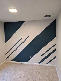 an empty room with blue and white stripes painted on the wall, carpeted floor