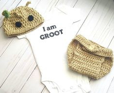 two crocheted baby onesuits and a handbag on a white wooden floor