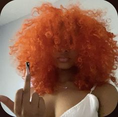 a woman with an orange curly wig pointing at her finger