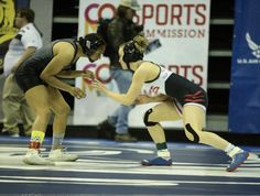 two women wrestling in a competition with one holding the other's hand out to her side