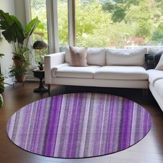 a living room filled with furniture and a large purple rug on top of a hard wood floor