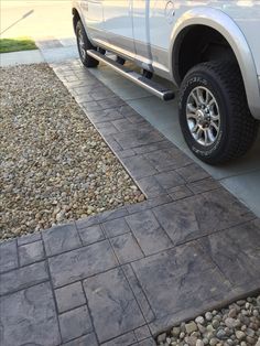 a white truck parked on the side of a road next to a gravel covered driveway